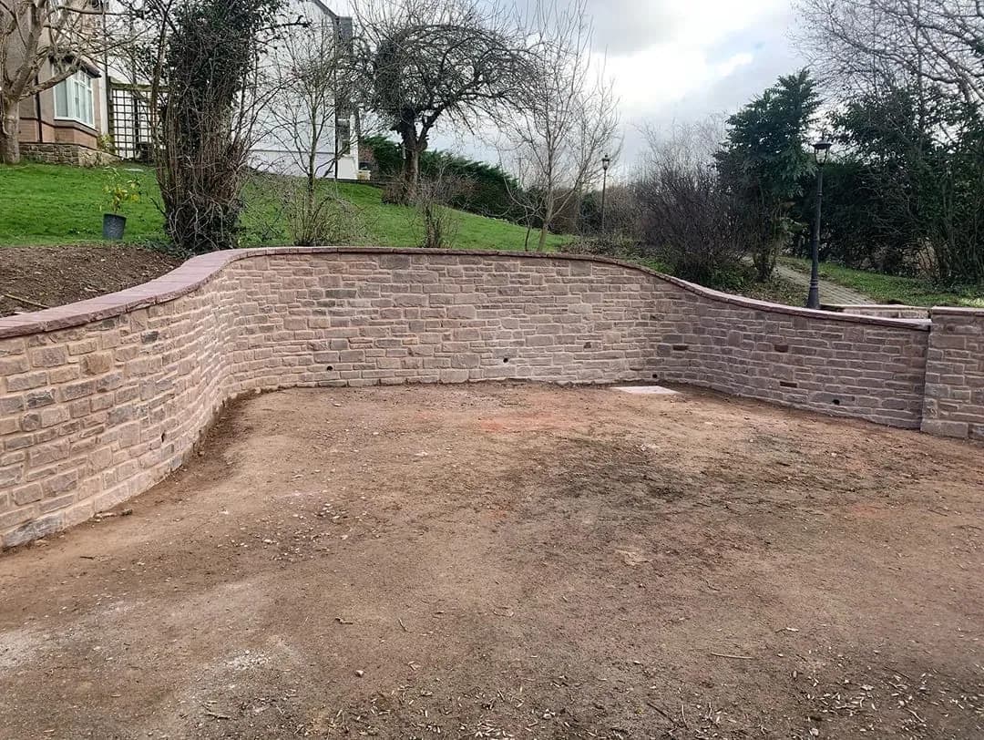 A curved sandstone retaining wall around a levelled garden, Monmouthshire