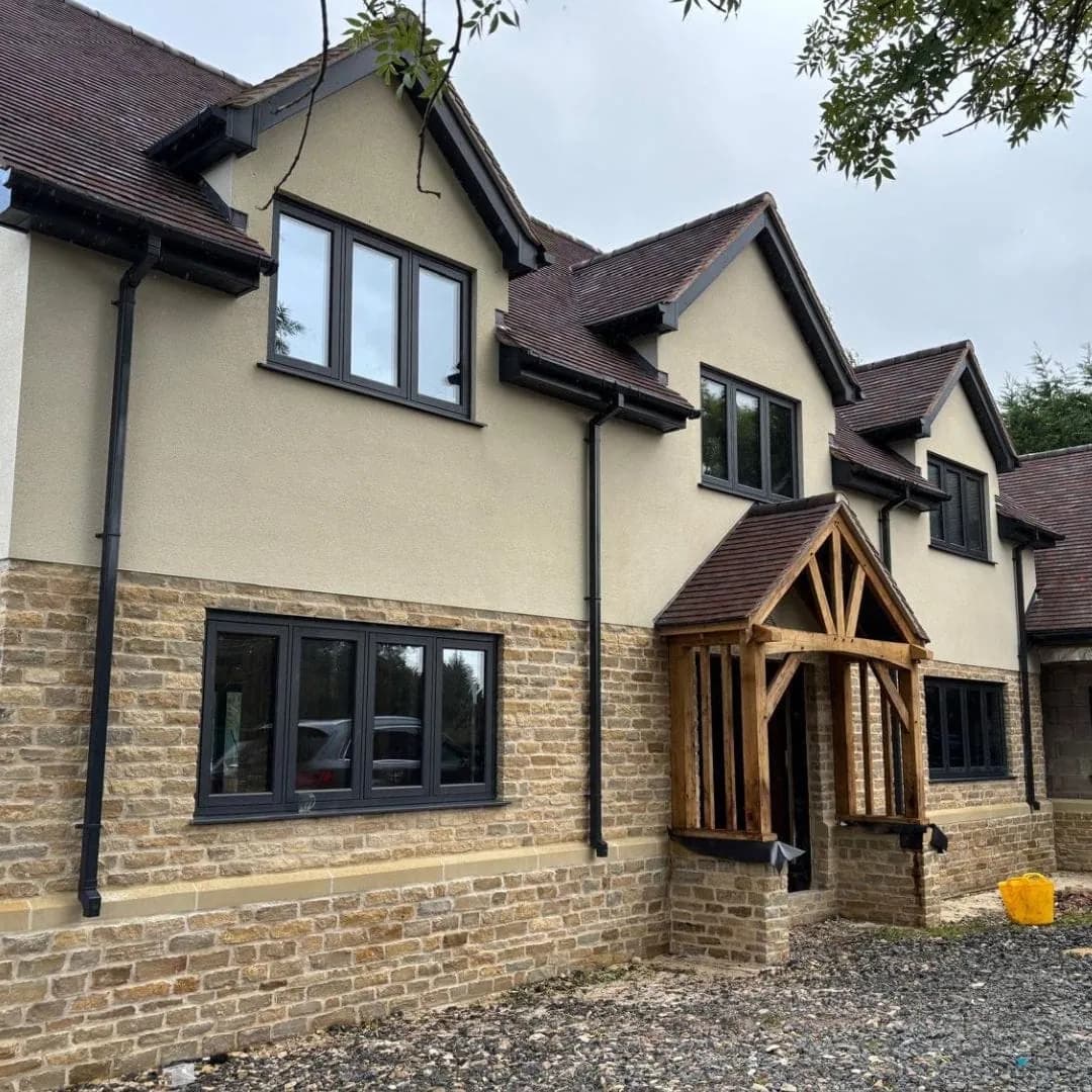 The finished house, Cotswold stone below and render above, with an oak porch, Herefordshire
