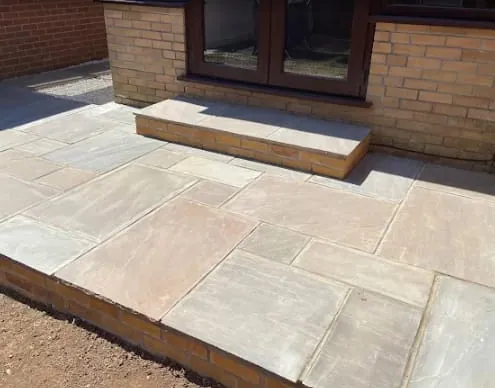 A new sandstone patio with a stone step up to the doors, Monmouthshire